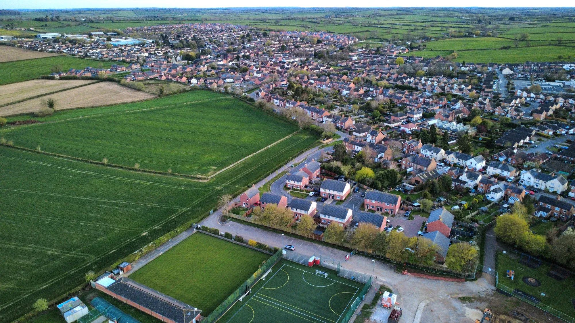 Aerial view of Fleckney showing the village, residential areas, and sports fields with lush green fields and community facilities.