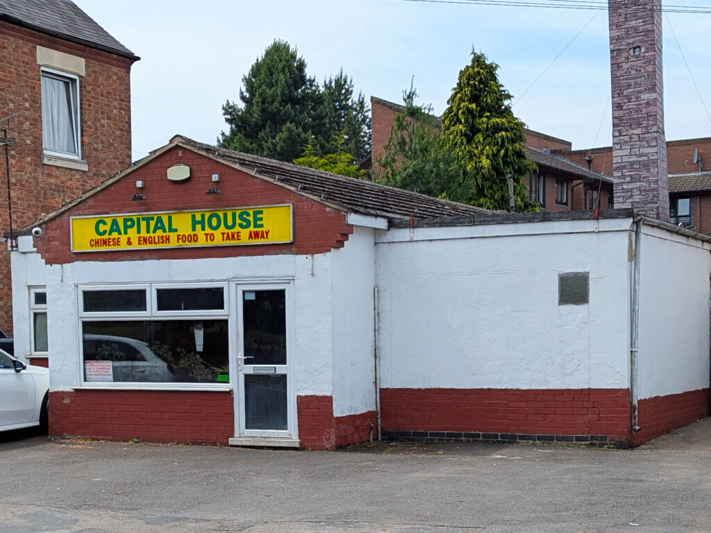 Exterior view of Fleckney Capital House, a Chinese and English takeaway restaurant, showing its white and red facade with a yellow signboard in a residential area.
