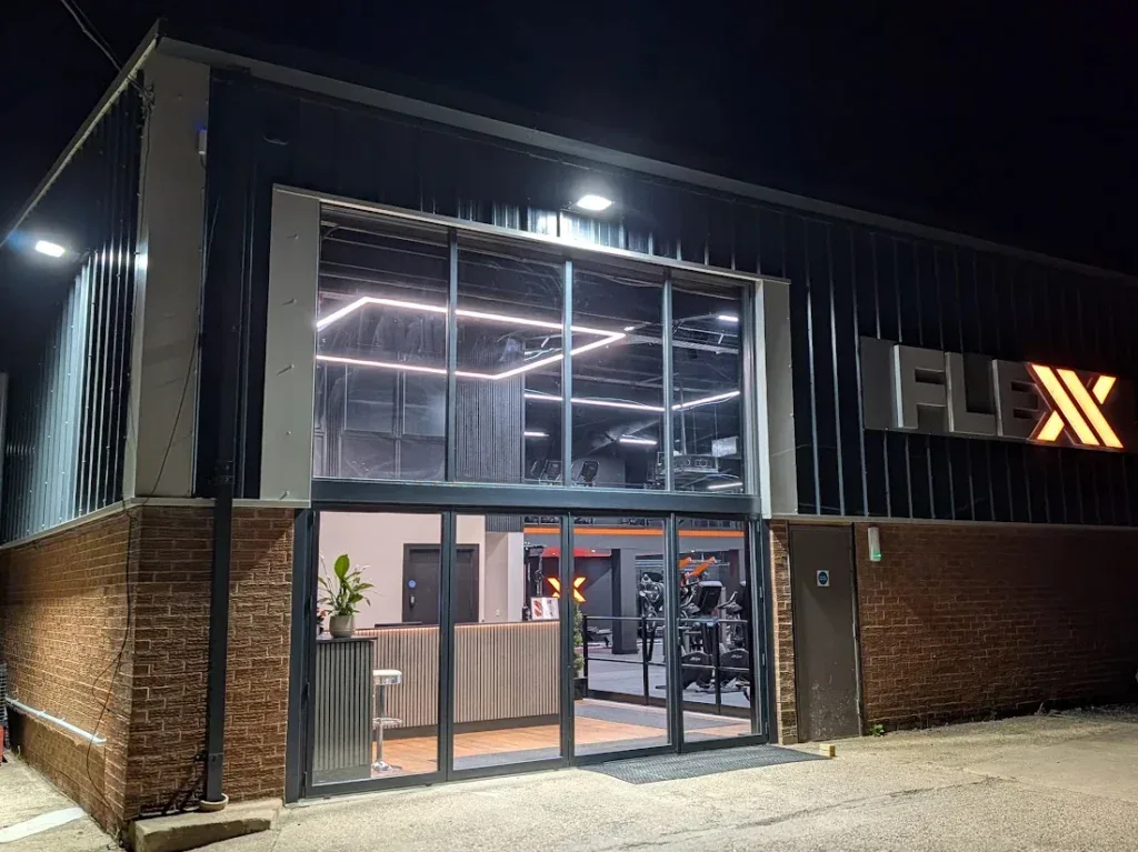 Fleckney Gym modern exterior with glass entrance, illuminated signage, and fitness equipment visible inside, located in Fleckney. Perfect for fitness enthusiasts seeking a local gym in Fleckney.