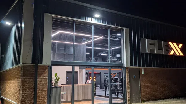 Fleckney Gym modern exterior with glass entrance, illuminated signage, and fitness equipment visible inside, located in Fleckney. Perfect for fitness enthusiasts seeking a local gym in Fleckney.