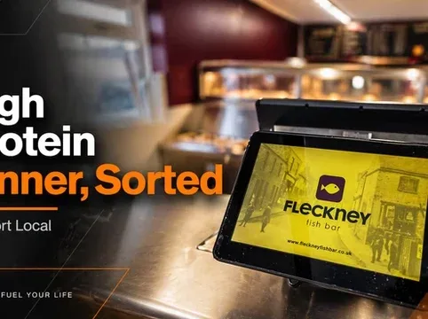Digital menu screen at Fleckney bar displaying food options in a modern setting.