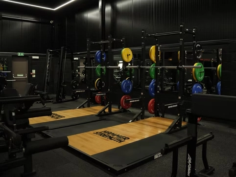Modern gym weightlifting area with barbells, weight plates, and lifting platforms for strength training.