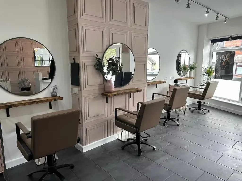Stylish hairdressing salon with contemporary styling stations, large mirrors, and comfortable chairs, creating a welcoming environment for clients seeking professional haircuts and treatments.