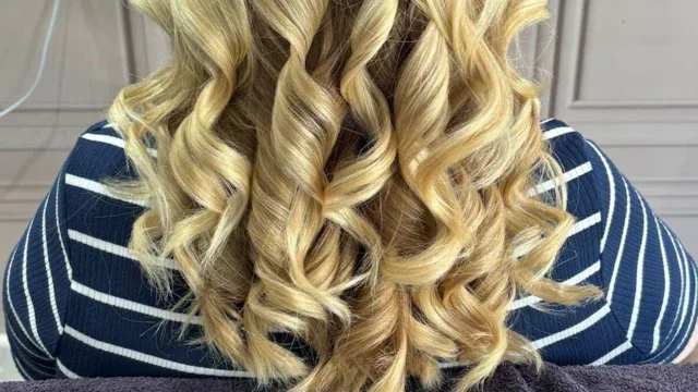 Elegant blonde hair with soft curls, showcasing professional styling services.