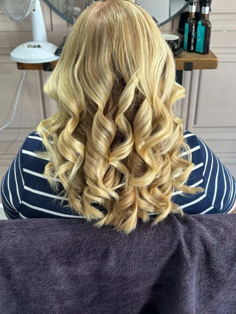 Elegant blonde hair with soft curls, showcasing professional styling services.