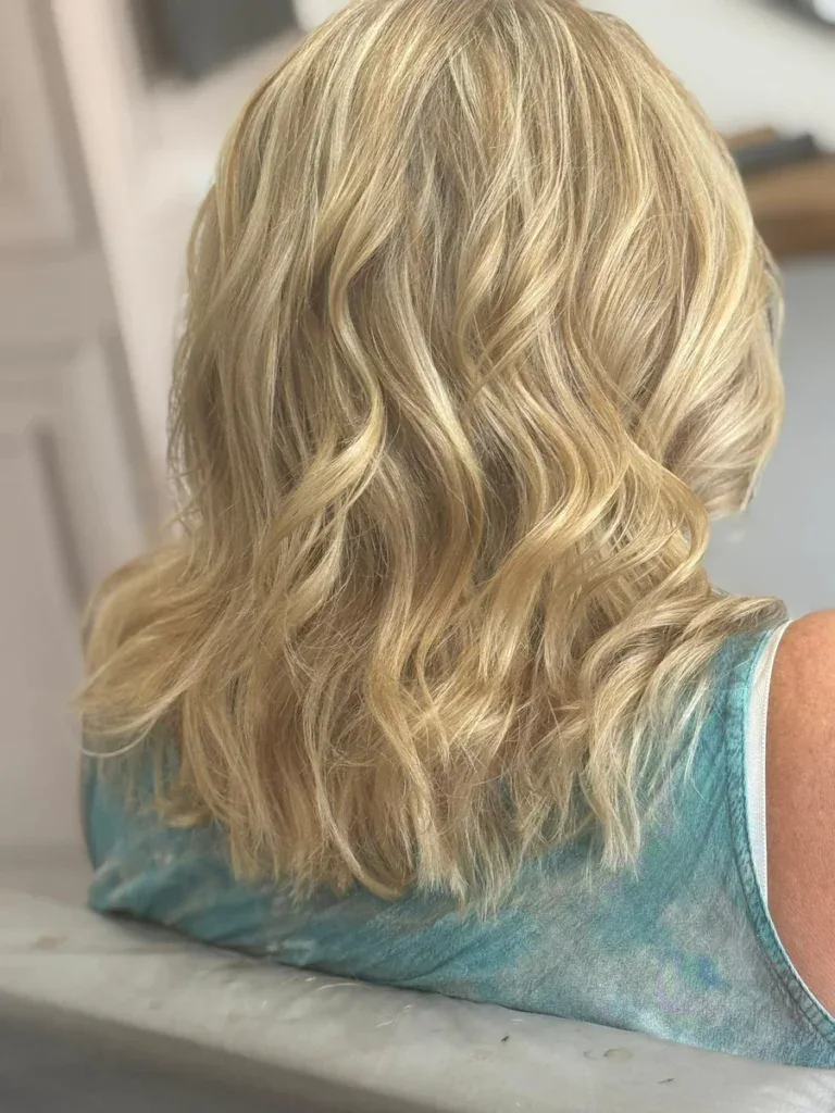 Close-up of a woman with shoulder-length, soft blonde wavy hair, showcasing healthy, shiny locks perfect for a casual or professional look.