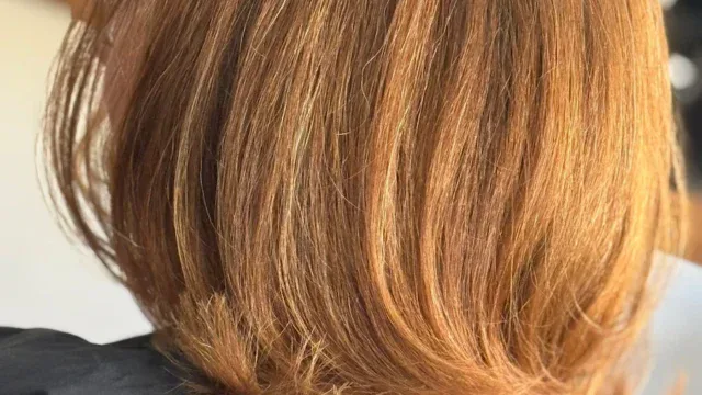 Close-up of a woman's freshly styled medium-length red hair with soft layers and a natural shine, showcasing professional hairdressing at Fleckney.Today.