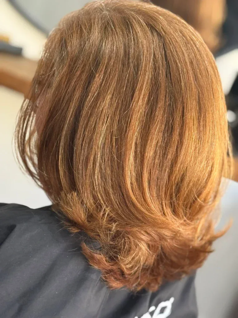 Close-up of a woman's freshly styled medium-length red hair with soft layers and a natural shine, showcasing professional hairdressing at Fleckney.Today.