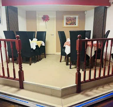A cosy dining area in Fleckney with elegant black chairs and round tables set for meals, featuring colourful wall art and a welcoming atmosphere.