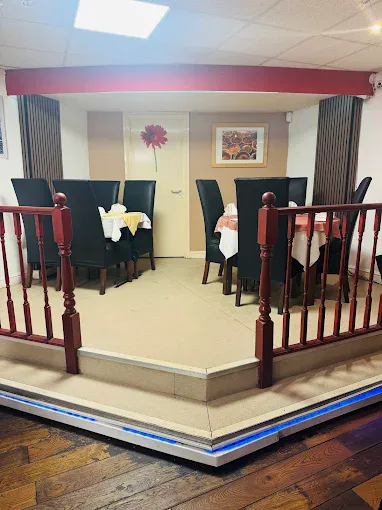 A cosy dining area in Fleckney with elegant black chairs and round tables set for meals, featuring colourful wall art and a welcoming atmosphere.