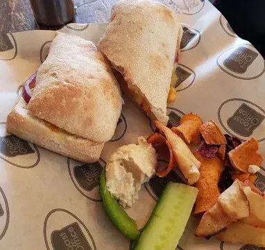 Fish finger sandwich with chips, cucumber, and tartar sauce on a wooden table.