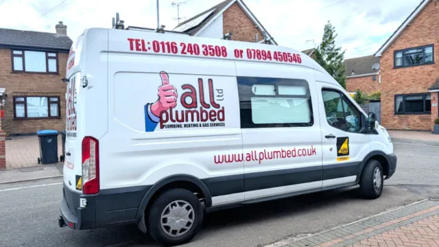 White plumbing service van for Fleckney with All Plumbed branding, contact numbers, and website, parked on a residential street.