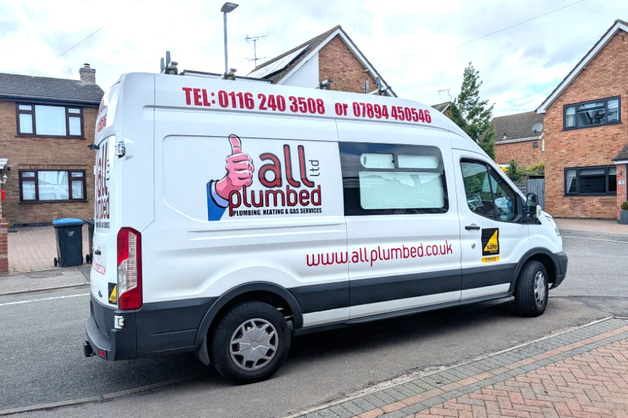 White plumbing service van for Fleckney with All Plumbed branding, contact numbers, and website, parked on a residential street.